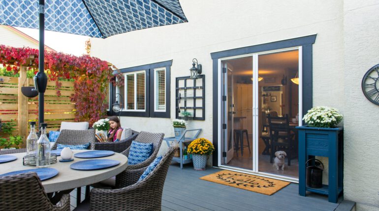 Family home patio with table, girl reading in chair and dog sitting in front of retractable double door screens