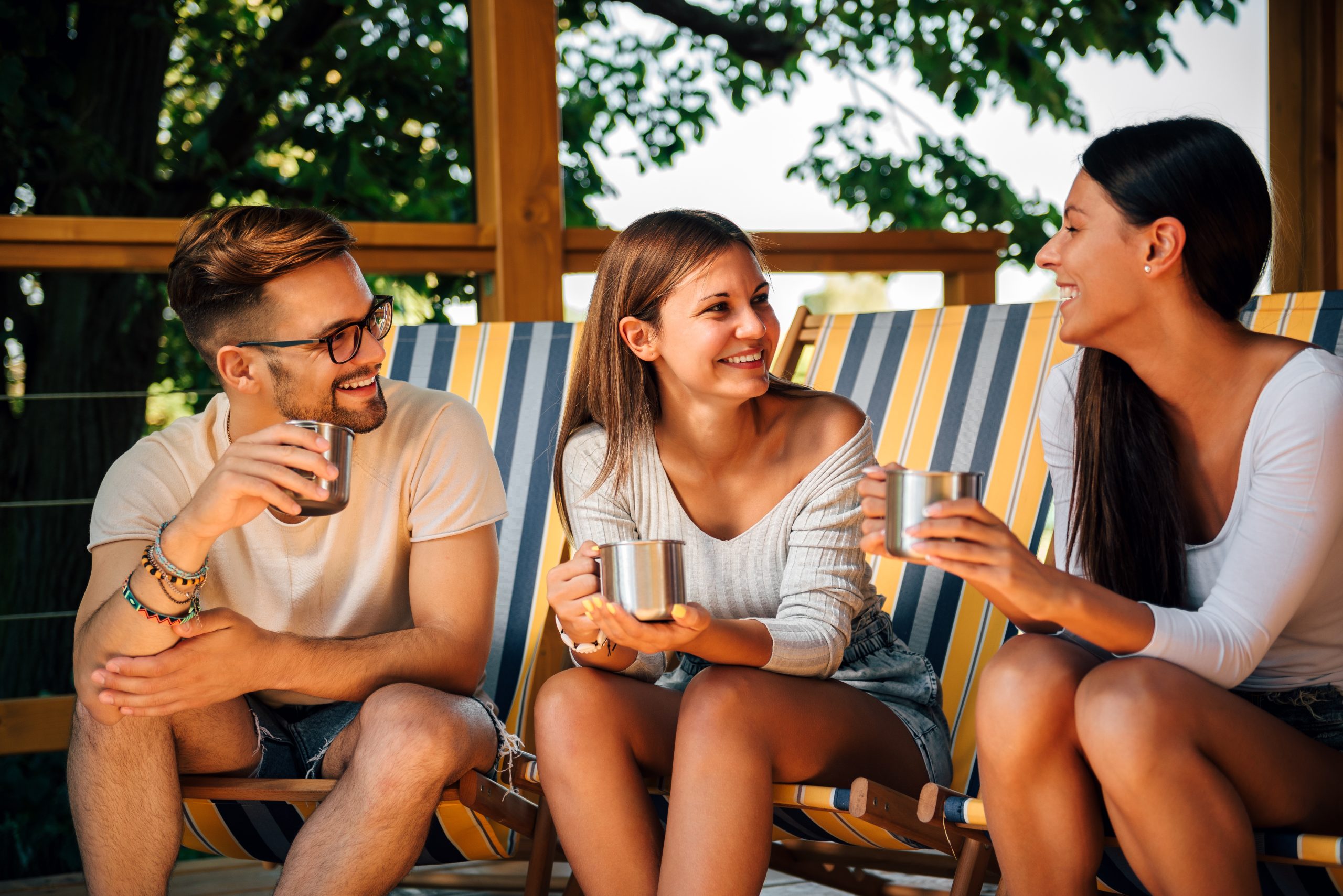three friends in camping chairs enjoying drinks