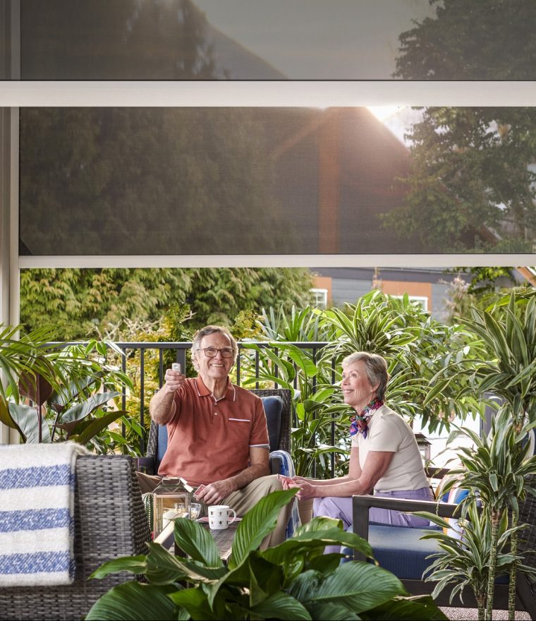 Elderly couple sitting on patio with motorized retractable screens